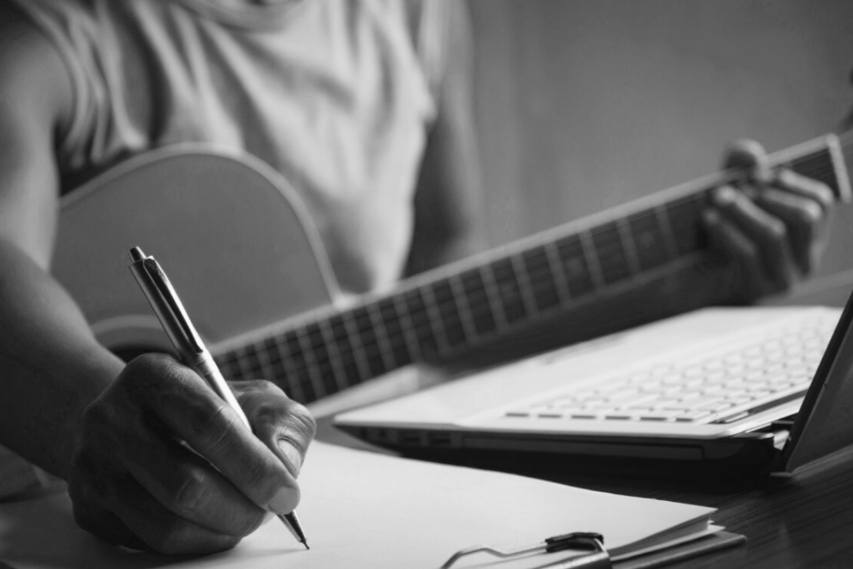 writing song with guitar in hand